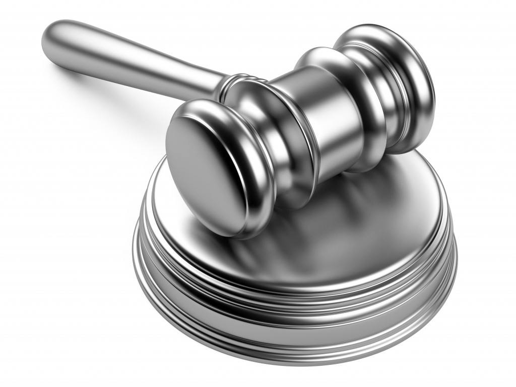 A silver gavel resting on a silver striking plate. Trust and estate planning.