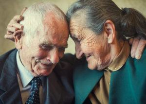 Elderly couple embracing one another endearingly.